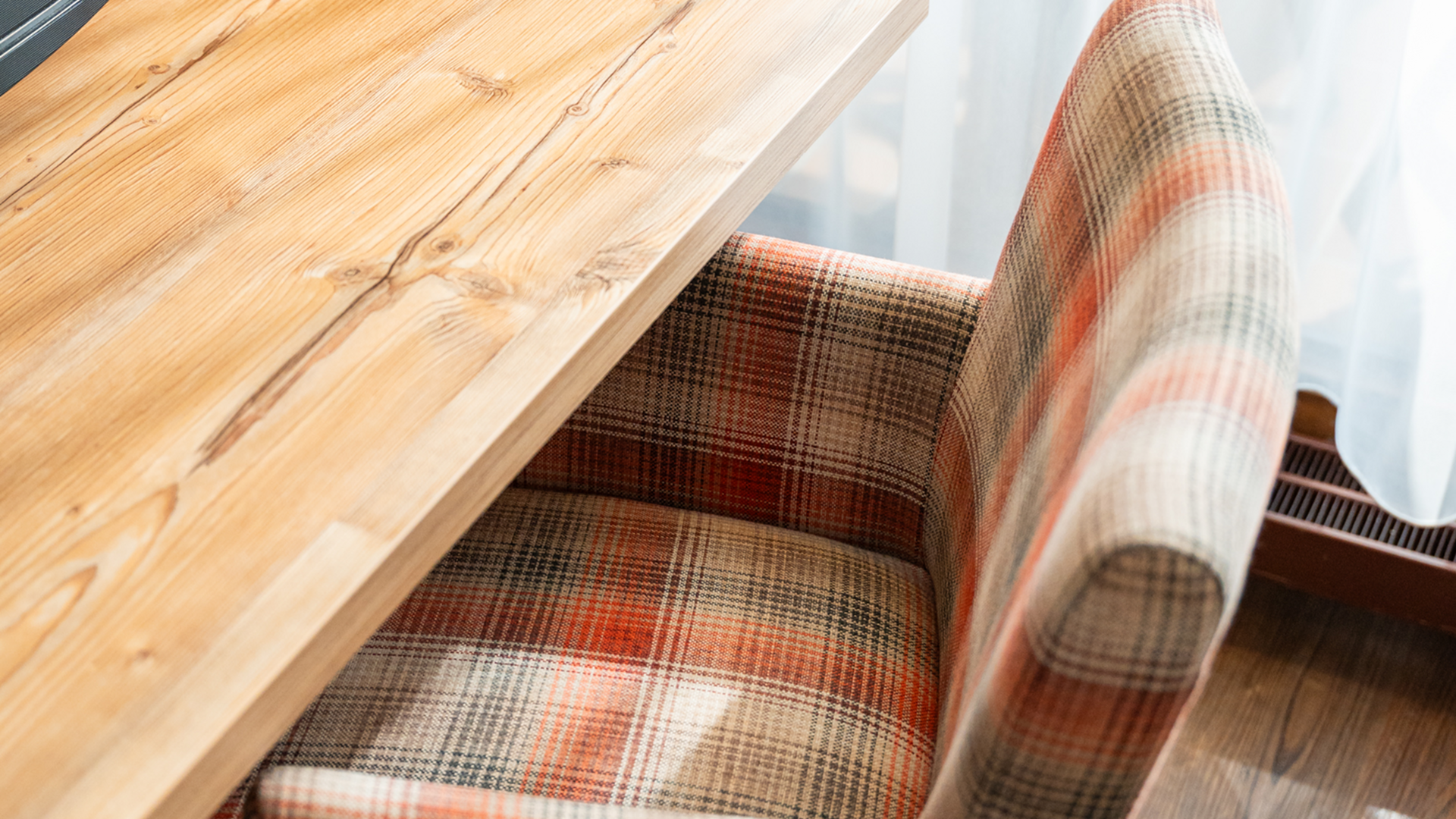 Schreibtisch aus Naturholz mit einem karierten Sessel im Hotel Vier Jahreszeiten am Schluchsee.