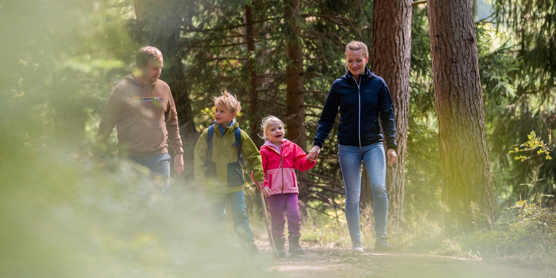 Kinder laufen voller Vorfreude einen Waldweg entlang während eines Familienausflugs.