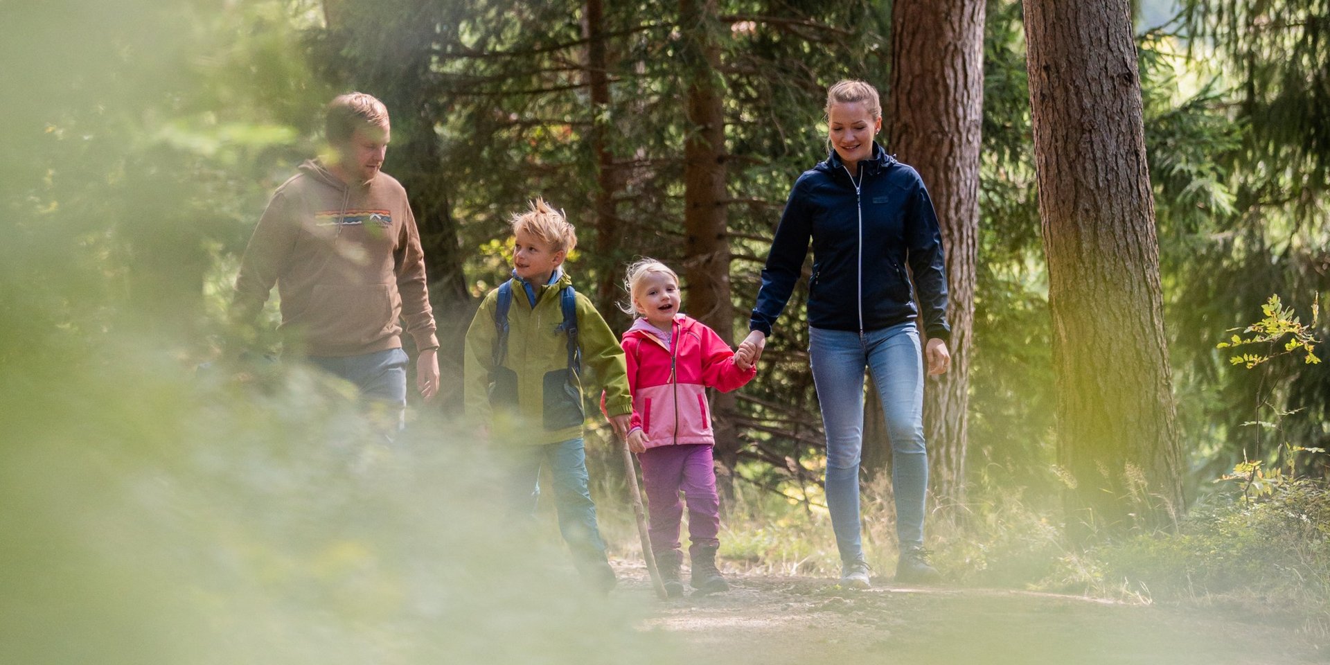 Kinder laufen voller Vorfreude einen Waldweg entlang während eines Familienausflugs.