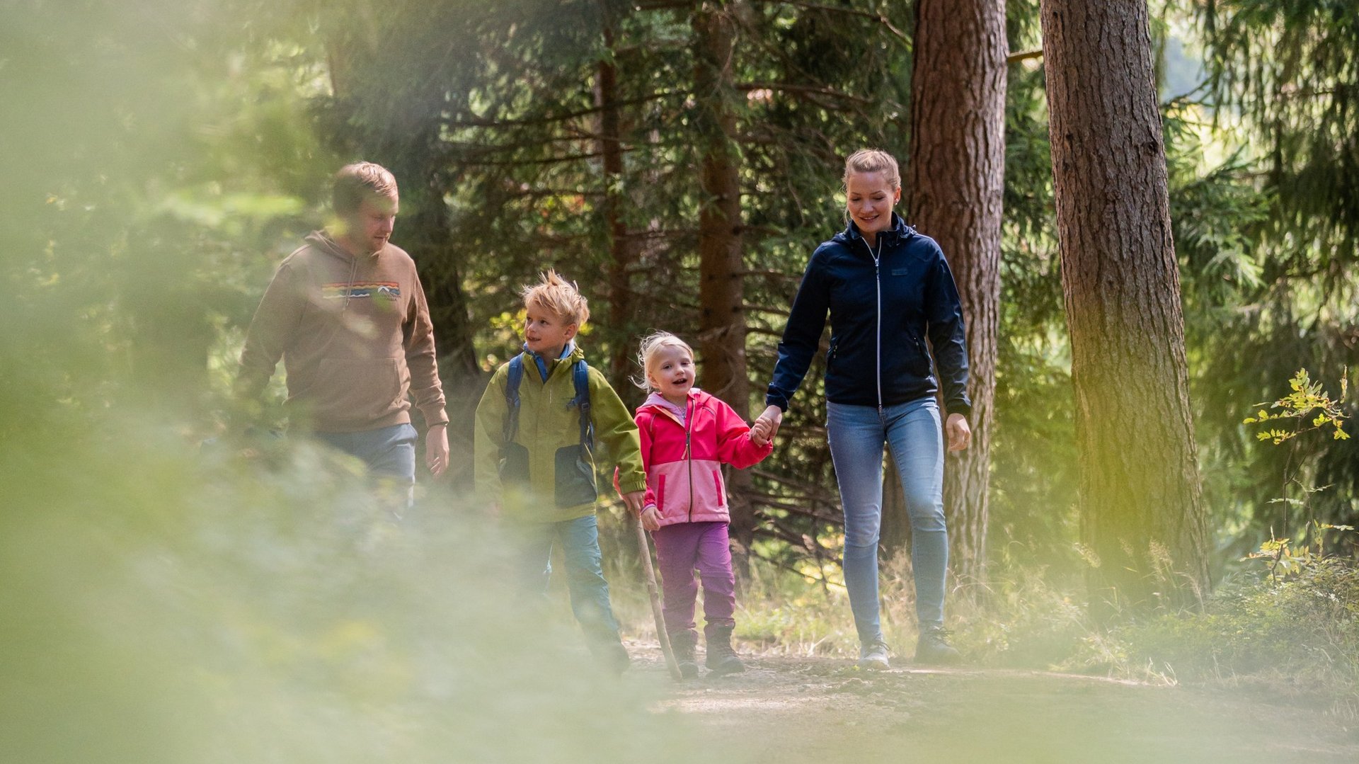 Kinder laufen voller Vorfreude einen Waldweg entlang während eines Familienausflugs.