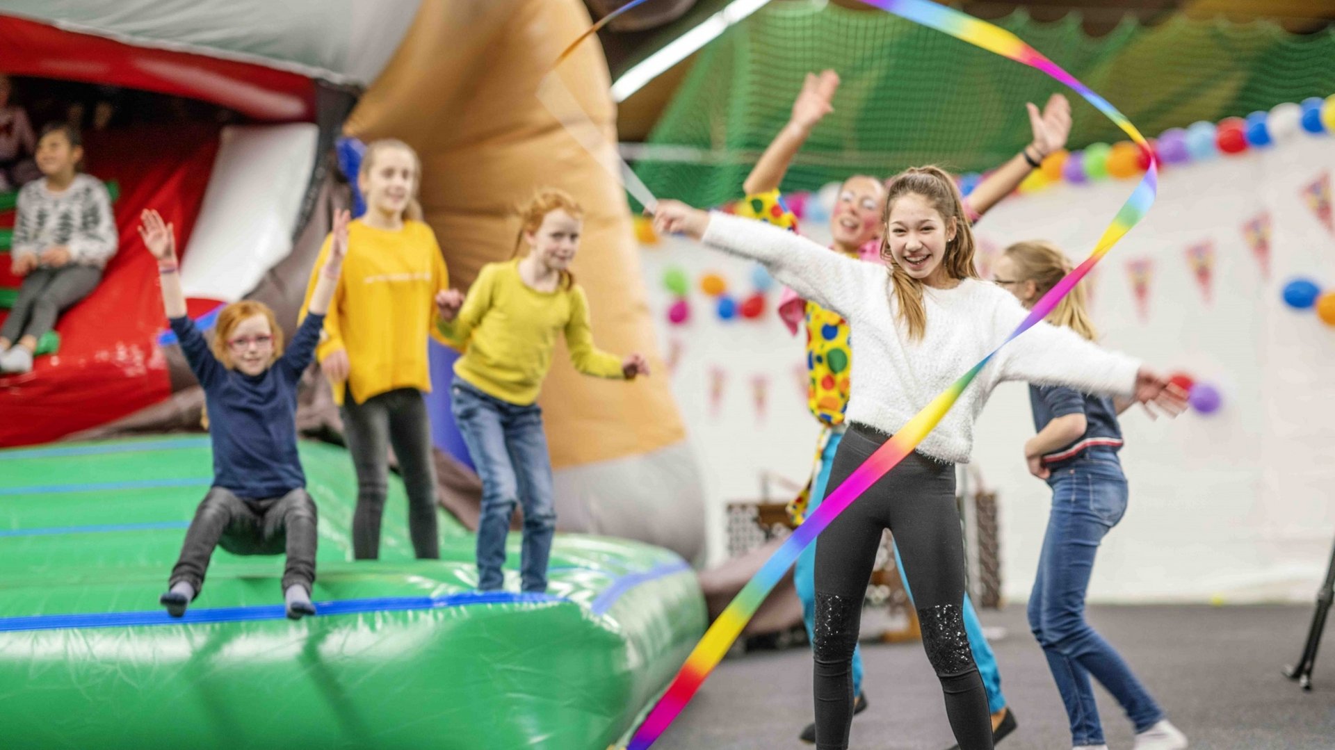 Kinder und Jugendliche springen ausgelassen auf und vor einer Hüpfburg im Hotel Vier Jahreszeiten.