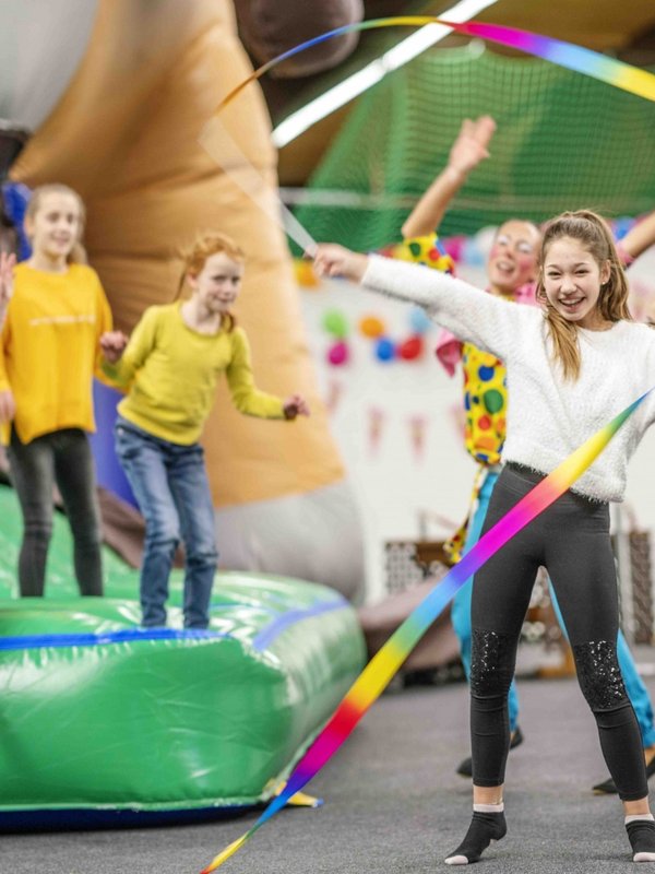 Kinder und Jugendliche springen ausgelassen auf und vor einer Hüpfburg im Hotel Vier Jahreszeiten.