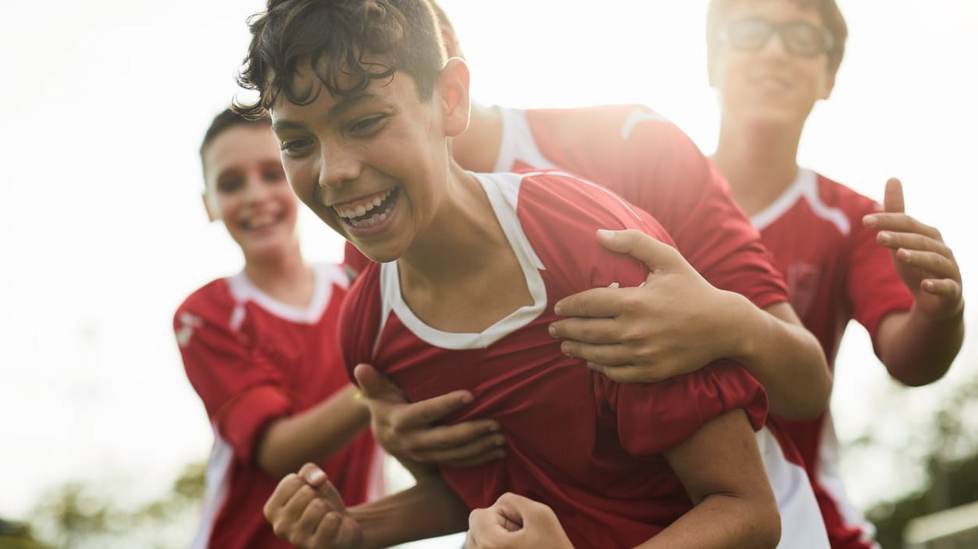Ein junger Fußballspieler jubelt enthusiastisch mit seinen Teamkollegen nach einem Tor.
