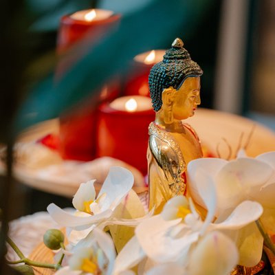 Eine kleine Buddha-Statue umgeben von brennenden roten Kerzen und weißen Orchideenblüten im Hotel Vier Jahreszeiten am Schluchsee.