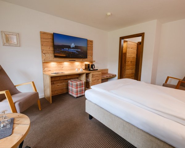 Blick in das wohnliche Einzelzimmer mit TV-Bereich und Schreibtisch.