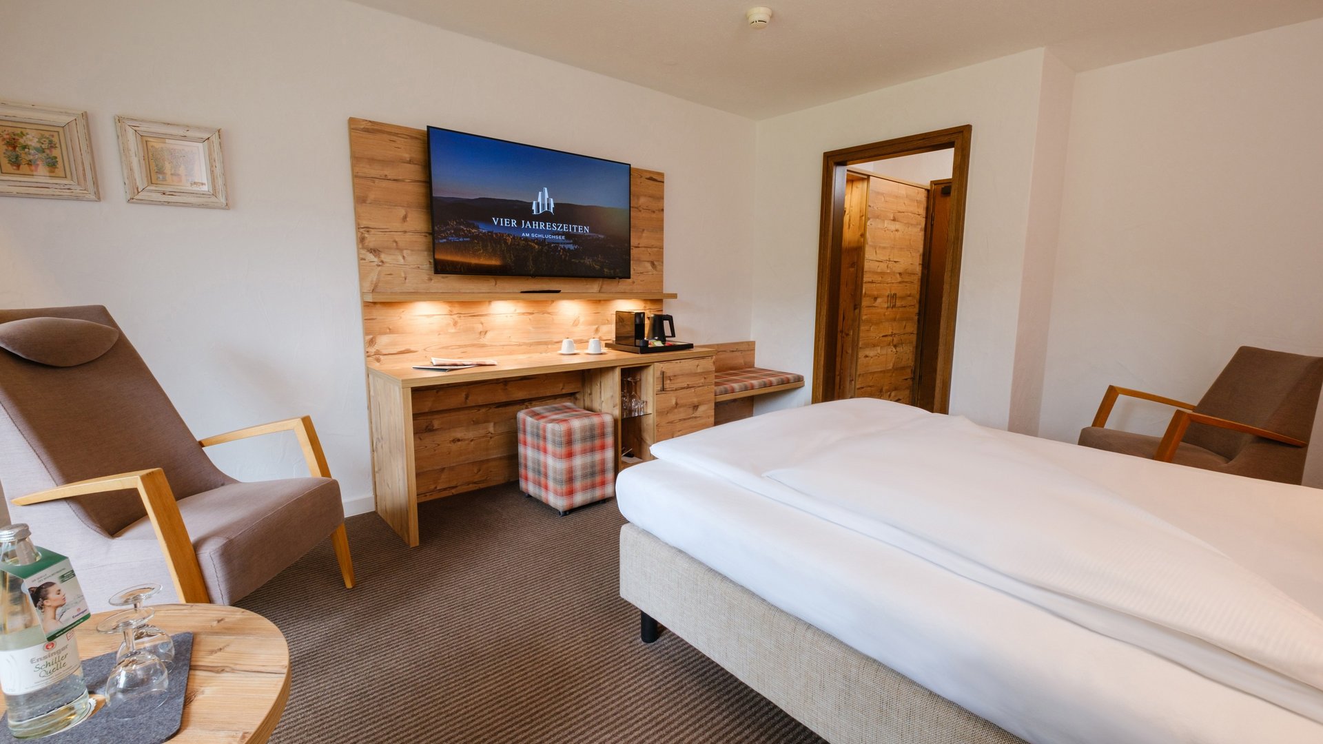 Blick in das wohnliche Einzelzimmer mit TV-Bereich und Schreibtisch.