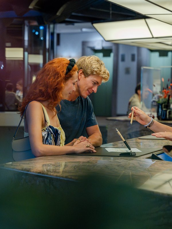 Ein junges Paar im Gespräch mit dem Team an der Bar des Hotels Vier Jahreszeiten am Schluchsee.