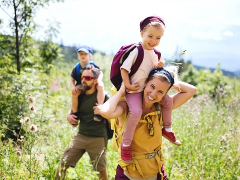 Familie beim Wandern mit Kindern auf den Schultern