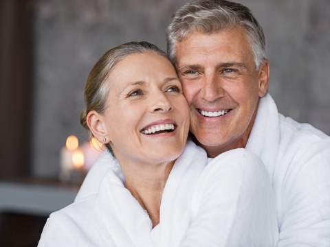 Best Ager Paar in Bademantel umarmt sich lachend