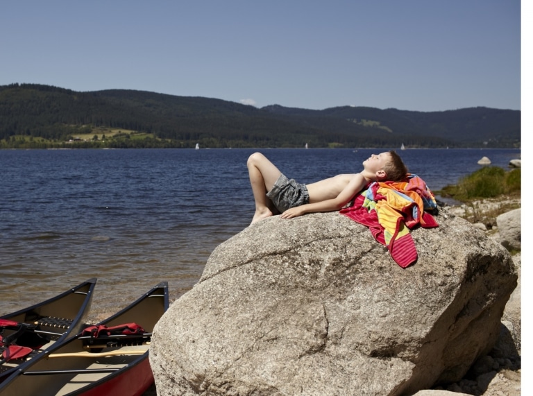 Junge beim Sonnenbaden auf einem Stein am Schluchsee © HTG
