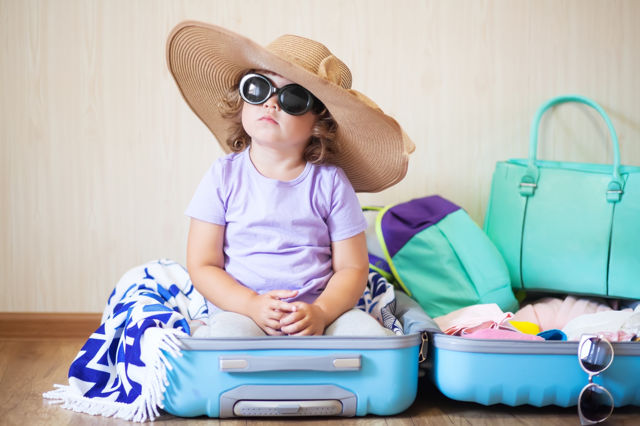 Kleines Mädchen mit Hut und Sonnenbrille im Koffer