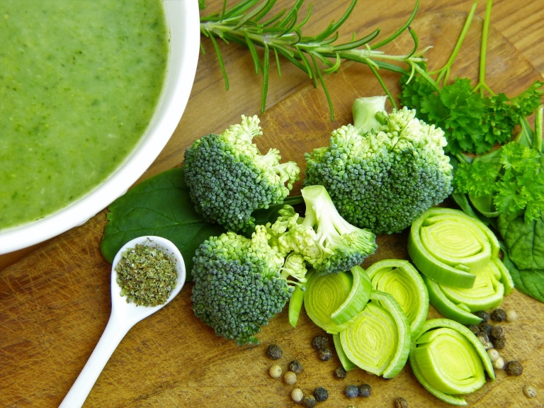 Grüne Suppe mit grünem Gemüse nebenan liegend