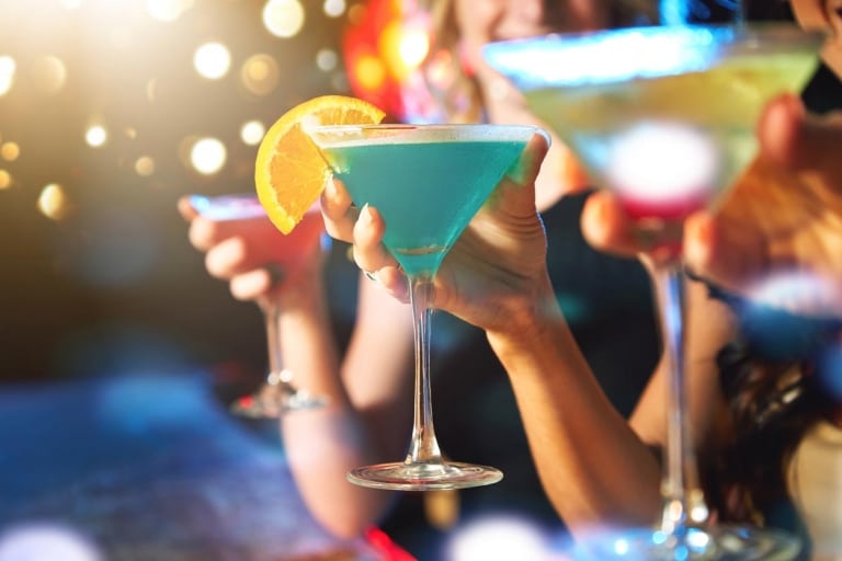 Blauer Cocktail mit einem Organgenschnitz im Fokus