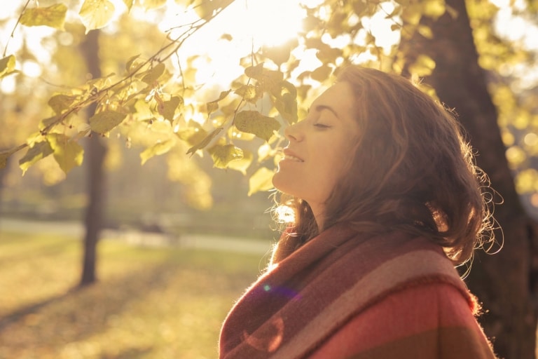 Frau genießt die Herbstsonne unter einem Baum
