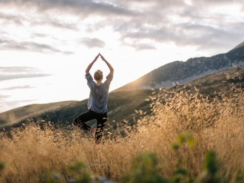 Frau beim Yoga in der Natur während des Sonnenaufgangs