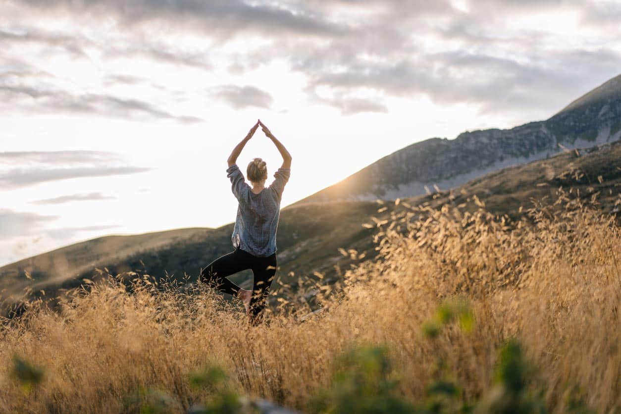 Frau beim Yoga in der Natur während des Sonnenaufgangs
